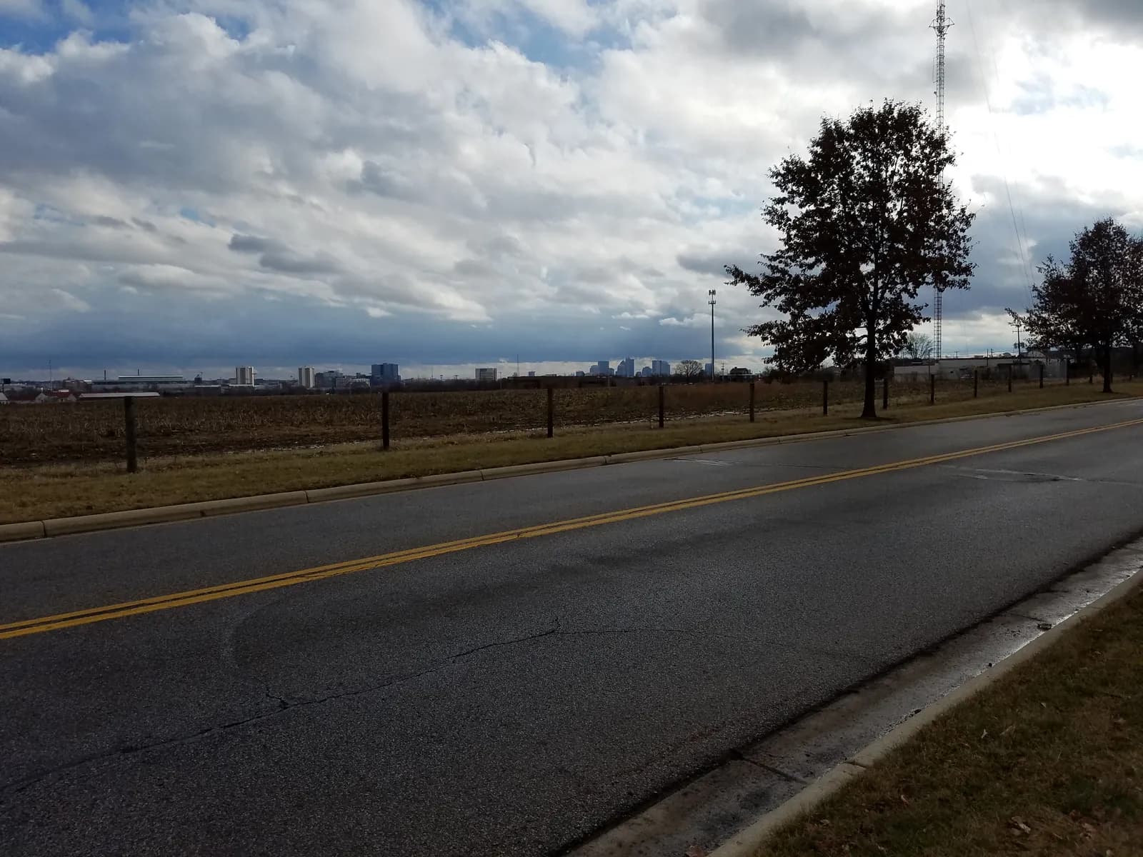 A road at the edge of Upper Arlington under dramatic clouds, with the Columbus skyline on the horizon